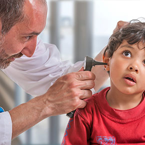 Picture of a male physician looking in a little boys ear with a otoscope.
